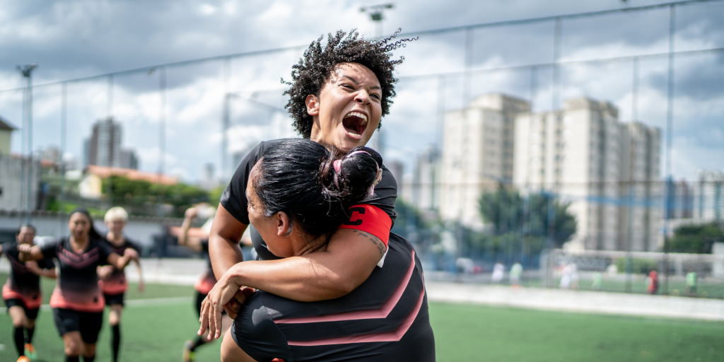 Jogadoras de futebol femininas comemorando abraçadas umas as outras