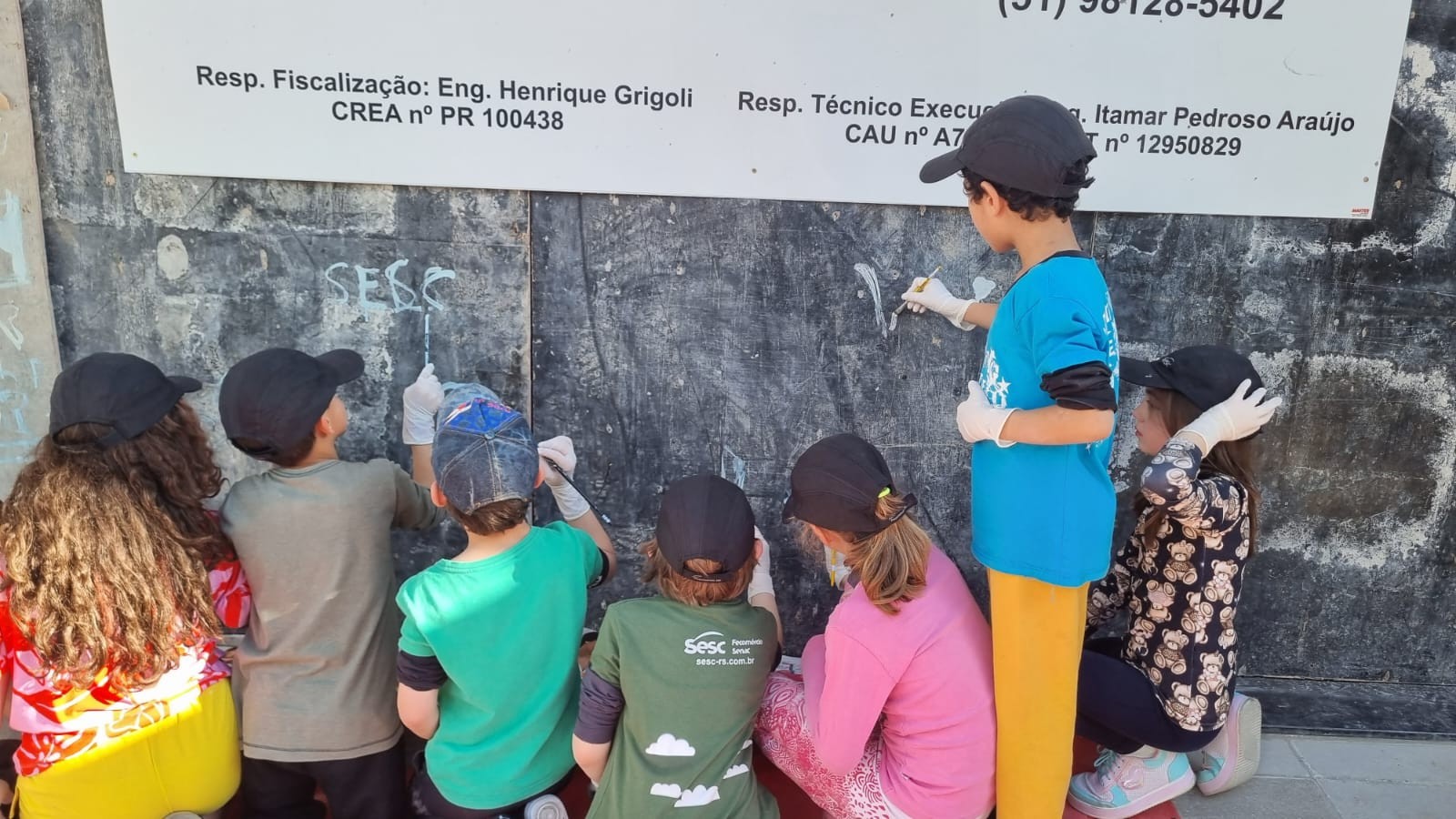Grupo de crianças desenhando nos muros de uma construção
