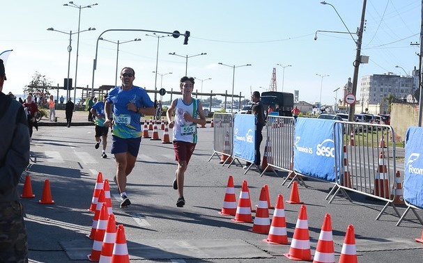 Imagem de um homem e um menino correndo, próximos a linha de chegada da corrida