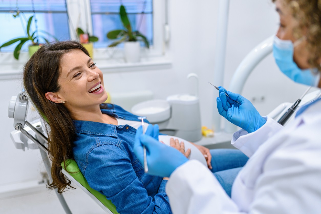 A imagem mostra uma gestante em atendimento na cadeira de um consultório odontológico.