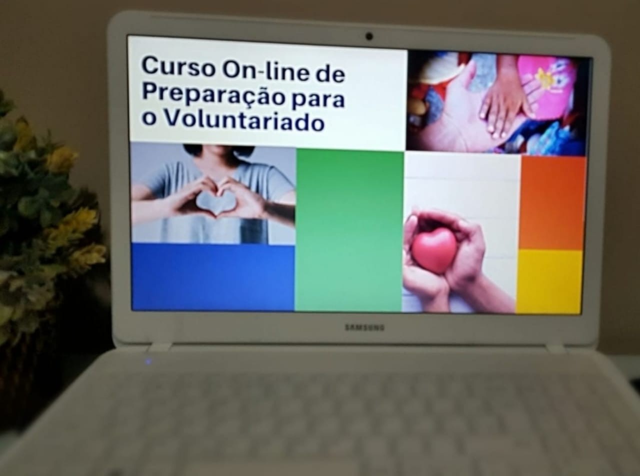 A imagem mostra a tela de um computador com slide do Curso On-line de Preparação para o Voluntariado.