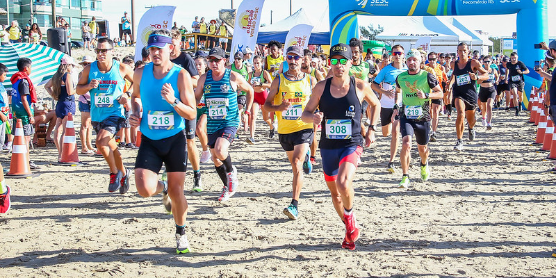 Corredores partindo da largada de uma maratona na areia