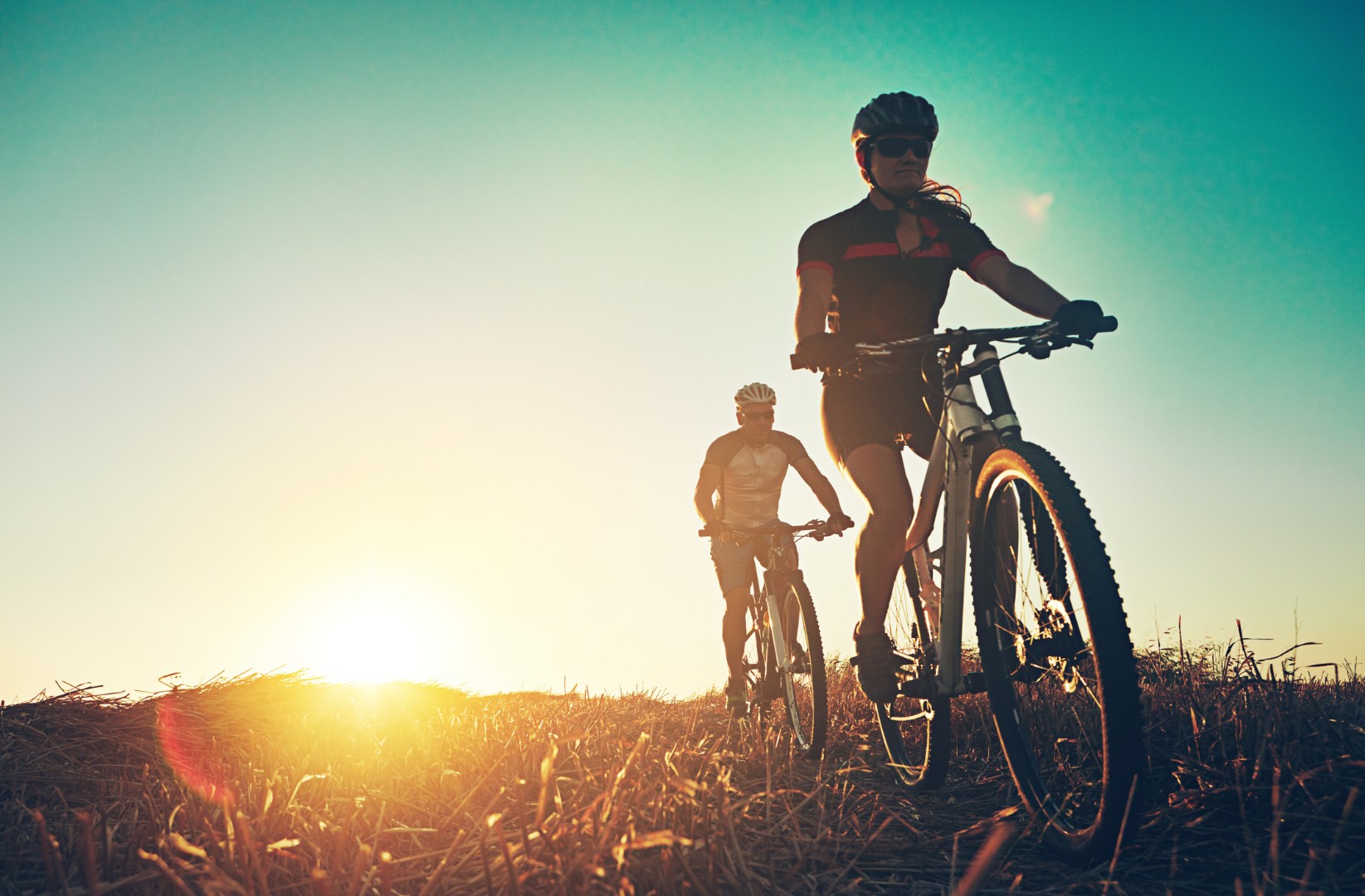 Duas pessoas andando de bicicleta no pôr do sol.