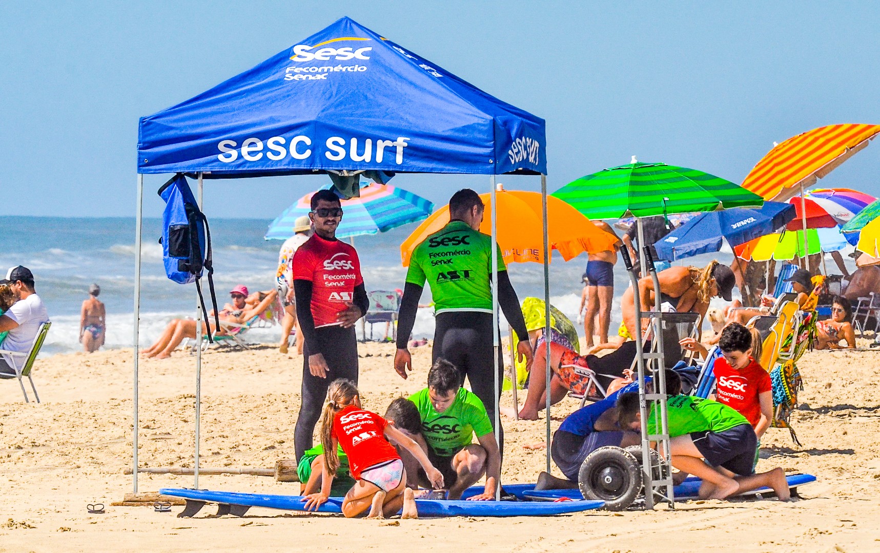 Profissionais do Sesc na praia assessorando alunos de surfe.