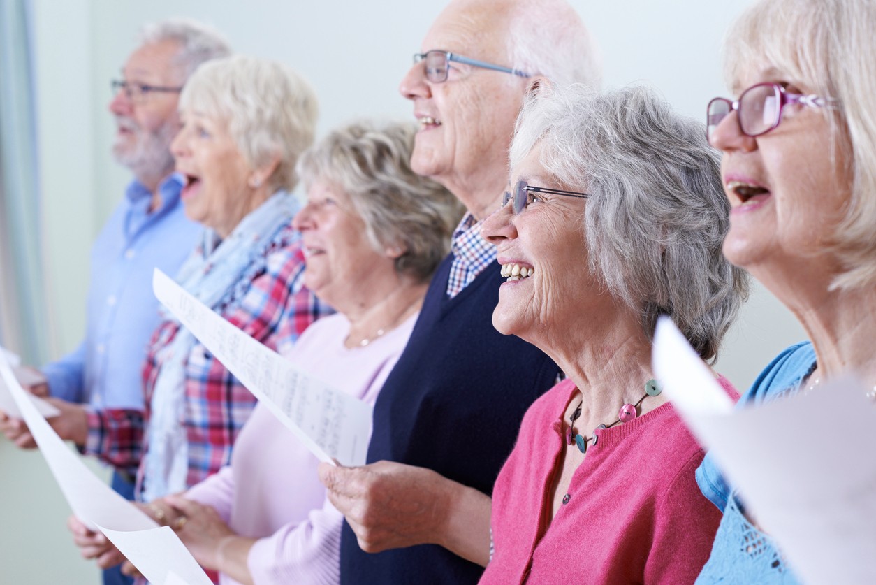 Imagem mostra grupo de idosos cantando em coral.