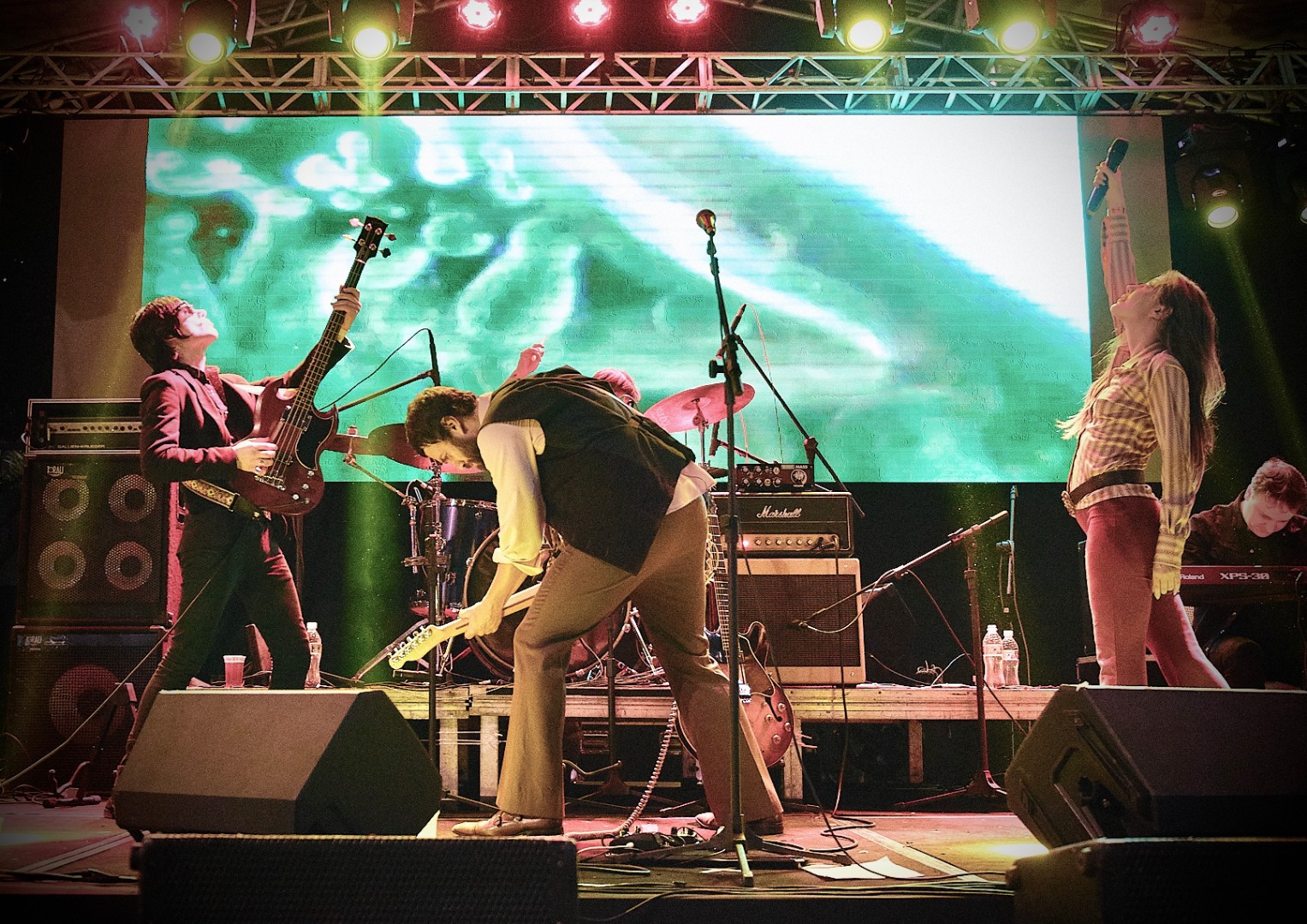 Ator e cantor Gabriel Braga Nunes tocando guitarra em um palco com a sua banda.