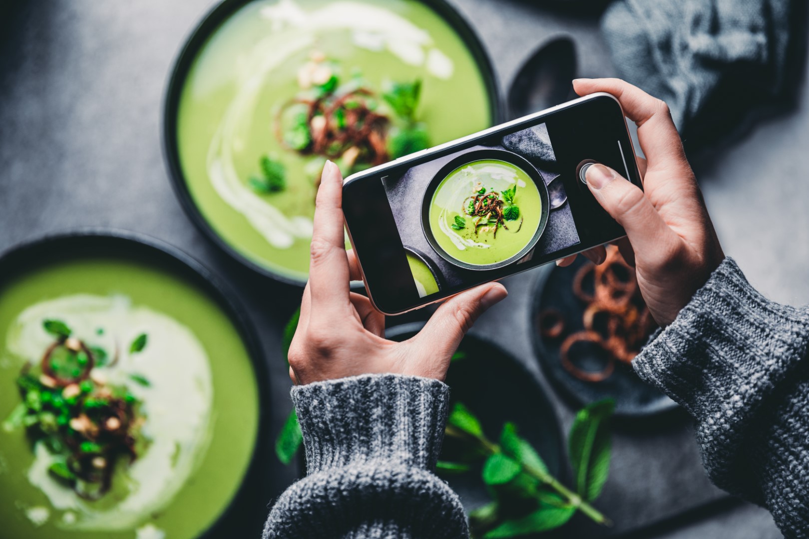 Mulher fotografando sopa verde fresca