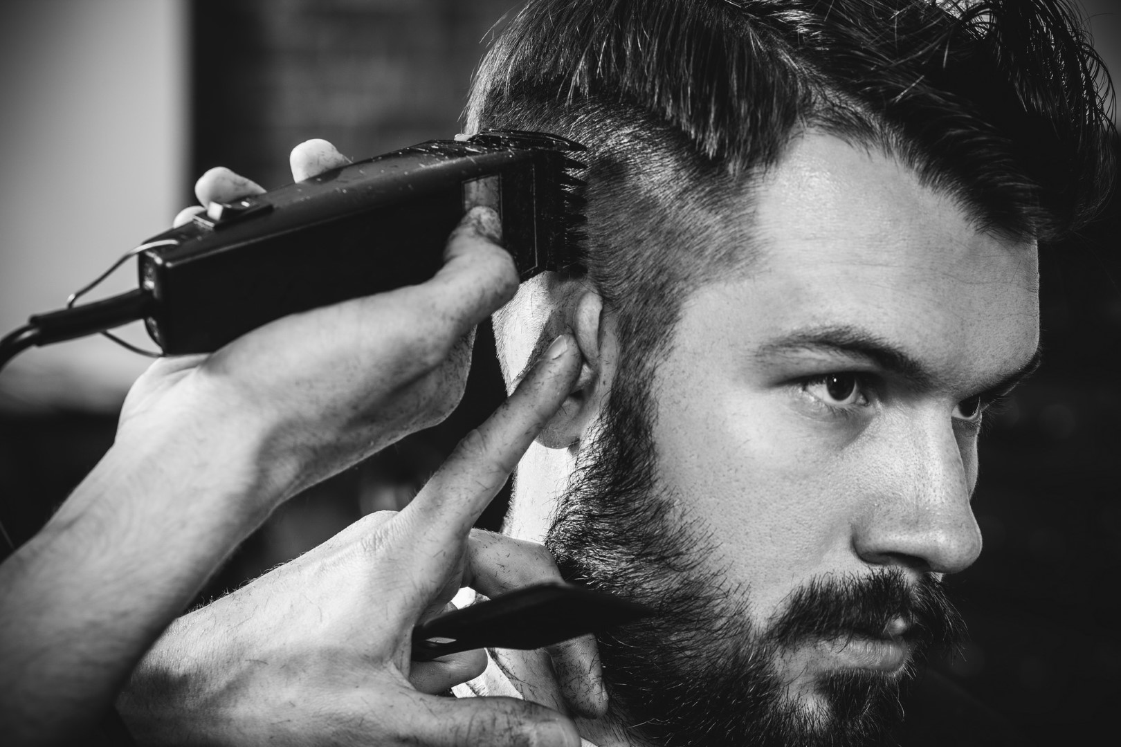 Homem sentado em uma salão e o barbeiro arrumando seu cabelo.