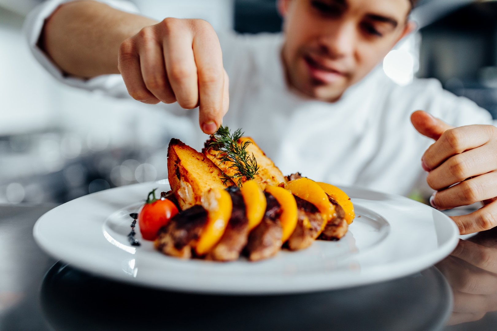 Foto de um jovem chef decorando a refeição na cozinha