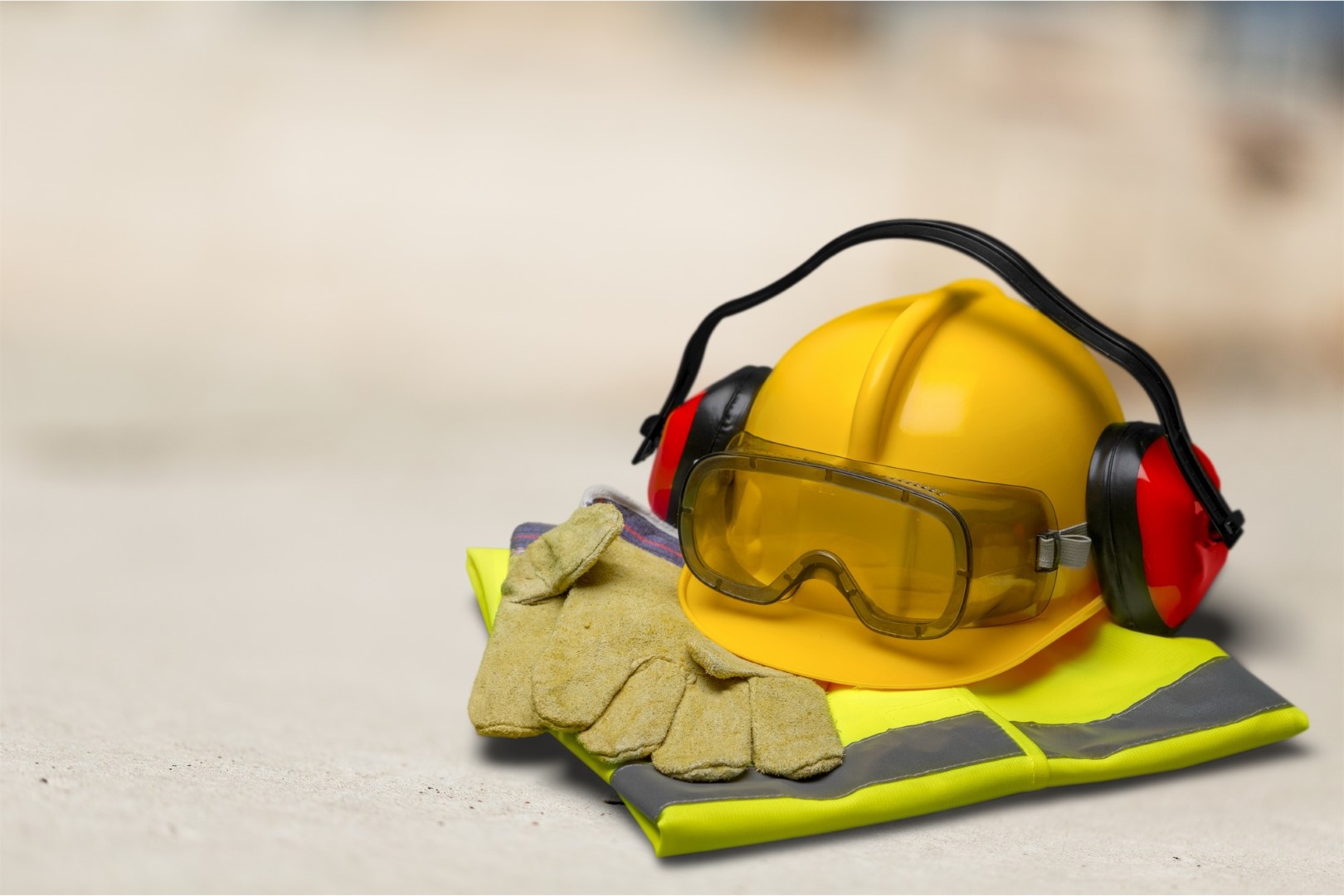 Capacete de segurança com fones de ouvido e óculos de proteção no fundo da construção