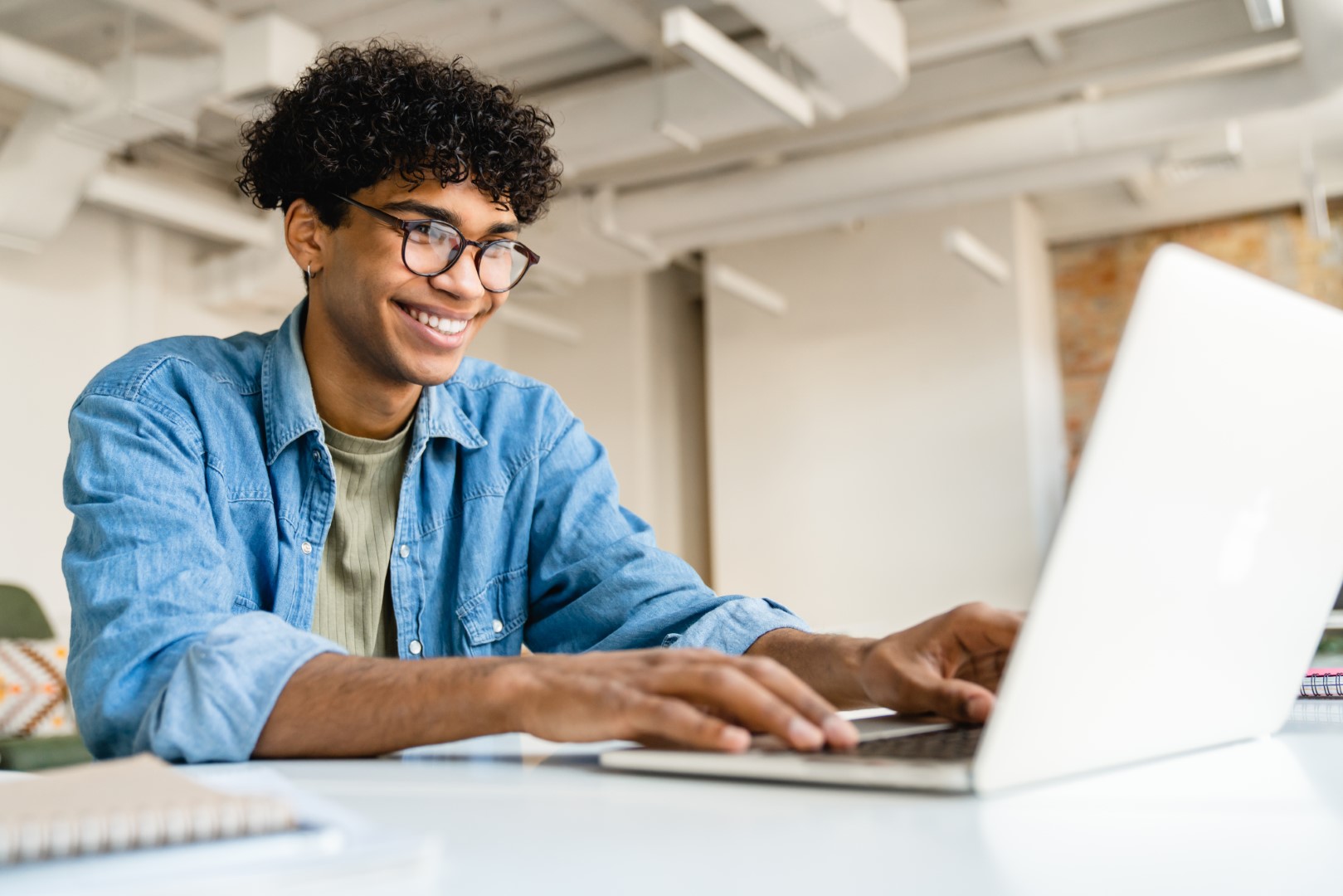 Feliz sorridente afro empresário usando laptop na mesa no escritório